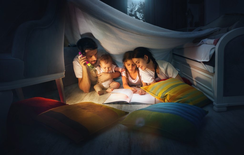 A small girl and grandmother reading book at home.