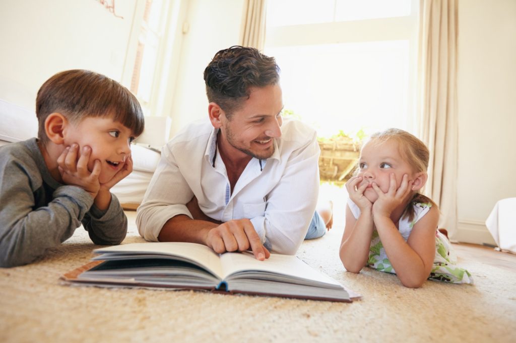 Young man with two kids reading a story book